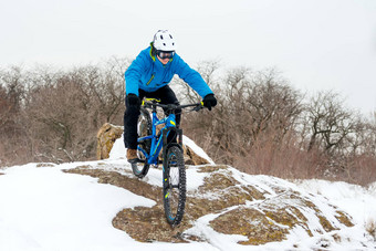 骑自行车的人蓝色的骑山自行车岩石冬天山覆盖雪极端的体育运动复古骑自行车概念