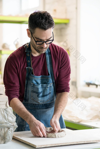 陶艺家穿着围裙工作生粘土明亮的陶瓷车间