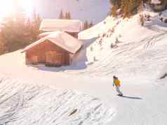 snowboardist滑雪坡高山小屋阳光明媚的一天阿尔卑斯山脉