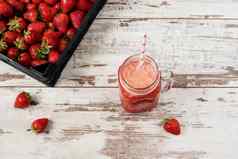 新鲜的汁摇奶昔草莓梅森Jar稻草桩多汁的成熟的有机新鲜的草莓黑色的箱草莓新鲜的喝光乡村木背景
