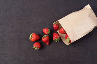 纸袋新鲜的红色的草莓新鲜的草莓小袋木风格表面小集团草莓黑暗木背景复制空间