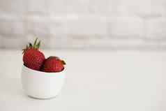 新鲜的草莓小白色碗白色背景砖墙明亮的作文