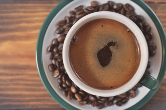 杯强大的咖啡泡沫飞碟咖啡豆子木背景