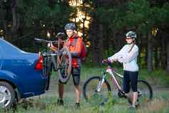 年轻的夫妇被卸载山自行车自行车架车冒险家庭旅行概念