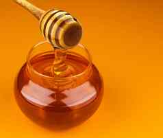 蜂蜜坚持碗倒蜂蜜孤立的黄色的背景