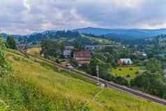 铁路通过山山坡上笼罩绿色植物村背景云雾弥漫山山峰多云的天空的地方休息旅游