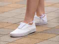 女运动鞋穿着女孩女孩站人行道上