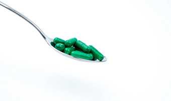绿色抗生素胶囊药片<strong>不锈钢勺子</strong>孤立的白色背景复制空间文本剪裁路径痤疮治疗健康政策健康保险概念