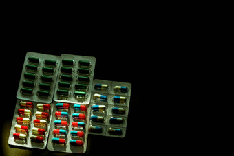 色彩斑斓的抗生素胶囊药片泡包黑暗背景复制空间医学感染疾病抗生素药物合理的药物电阻医疗保健概念