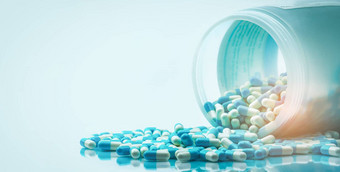 蓝色的白色胶囊药丸泄漏白色塑料瓶容器全球医疗保健概念抗生素药物电阻抗菌胶囊药片制药行业