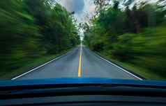 前面视图蓝色的车开车快速度中间沥青路白色黄色的行交通象征绿色森林树路模糊车模糊运动