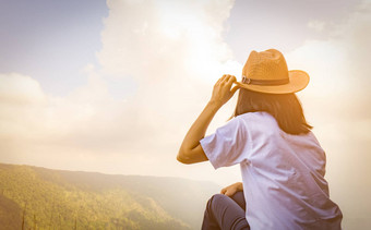 年轻的<strong>旅行</strong>女人穿他<strong>坐</strong>着前山悬崖放松情绪看美丽的视图森林蓝色的天空云假期亚洲女人<strong>旅行</strong>