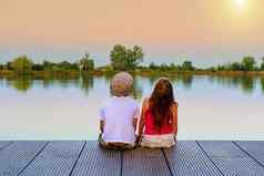 男孩平帽女孩坐着码头男孩女孩向上天空爱友谊童年概念美丽的浪漫的日落图片