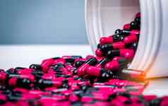 粉红色的黑色的胶囊药丸泄漏白色塑料瓶容器处方药物抗生素药物电阻抗菌胶囊药片制药行业药店背景