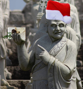 圣诞节石头佛教和尚雕像指出礼物空白卡持有穿红色的圣诞老人老人他