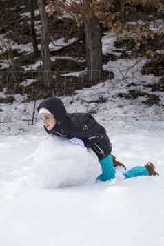 青少年女孩温暖的冬天衣服使雪人森林