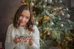 年轻的女人持有光加兰圣诞节树