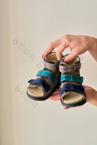 女持有特写镜头特殊的孩子们的整形鞋凉鞋使真正的皮革