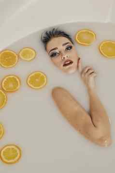 年轻的女人浴牛奶橙子片