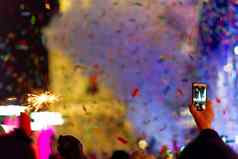 一年庆祝活动主要广场很多烟雾灯salute五彩纸屑模糊色彩斑斓的背景孟加拉语火手手套前景电话录音机手音乐会场景蓝色的光一边框架