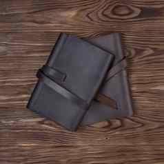 黑色的棕色（的）手工制作的皮革笔记本涵盖了木背景股票照片奢侈品业务配件视图