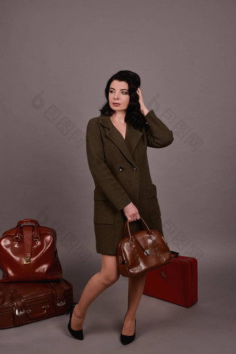 工作室肖像女人经典外套摆姿势集复古的手提箱<strong>手袋</strong>灰色的背景