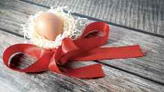 鸡蛋巢稻草红色的缎丝带木表格