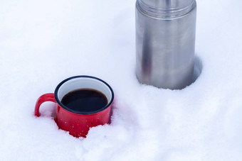 红色的金属杯咖啡倒热水瓶纯白色雪森林走