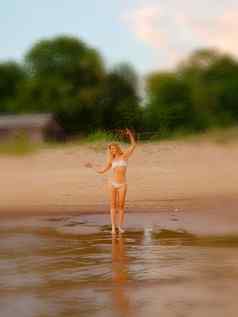 夏天假期假期海滩概念金发女郎女孩白色比基尼摆姿势海滩背景模糊