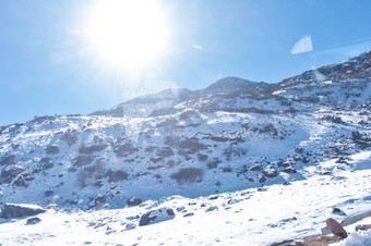太阳前雪封面喜马拉雅山脉范围冻岩石峰填满深雪照亮不断上升的阳光冷淡的冬天一天时间蓝色的清晰的天空云路径太阳风景如画的自然美