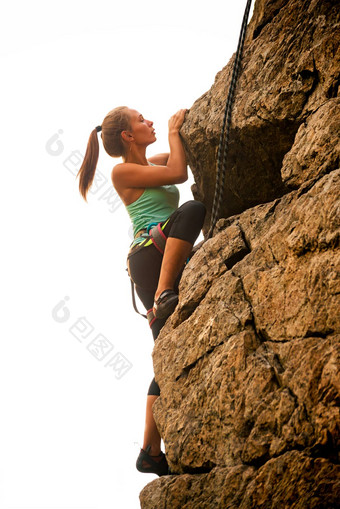 美丽的<strong>女人</strong>攀爬岩石多雾的日落山冒险极端的体育运动概念