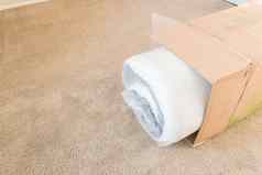 特写镜头前视图roll-packed春天床垫从箱子中取出地毯地板上背景