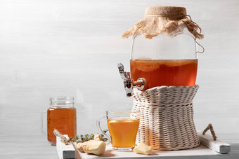 新鲜的自制的红茶菌发酵茶喝Jar水龙头杯杯子白色托盘木背景Copyspace
