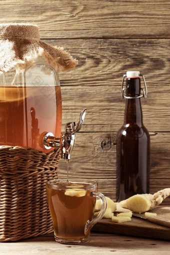 新鲜的自制的红茶菌发酵茶喝Jar水龙头杯瓶木背景垂直图像