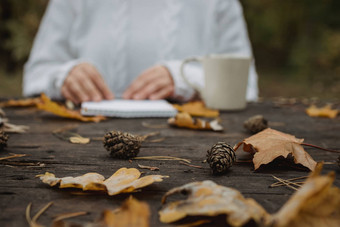年轻的女人白色毛衣坐在黑暗表格公园持有杯茶咖啡读取写背景<strong>黄</strong>色的秋天叶子温暖的秋天<strong>大气</strong>软焦点复制空间