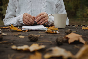年轻的女人白色毛衣坐在黑暗表格公园持有杯<strong>茶</strong>咖啡读取写背景黄色的秋天叶子温暖的秋天<strong>大气</strong>软焦点复制空间