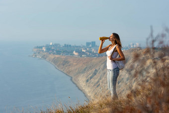 女孩饮料瓶水站背景山海景观
