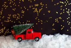 微型红色的玩具车携带圣诞节树屋顶雪黑暗背景闪亮的星星复制空间圣诞节作文明信片模板