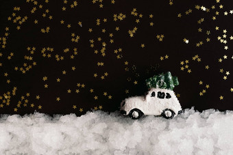 微型白色玩具车携带圣诞节树屋顶雪黑暗背景闪亮的星星复制空间圣诞节作文明信片模板