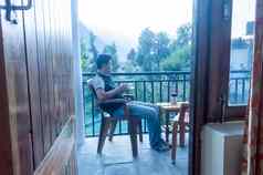 成熟的成人旅游只有业务旅行者印度种族冬天服装坐着阳台假期别墅持有热杯茶早....山城市背景旅行假期活跃的生活健康的生活方式概念