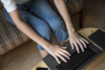 女人坐着沙发移动PC木表格研究工作在线自由使用女孩工作笔记本坐着沙发上电话ereader表格