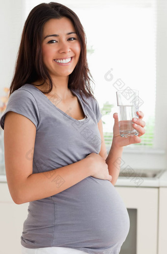美丽的怀孕了女人持有<strong>玻璃水</strong>站