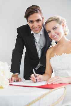 肖像漂亮的年轻的夫妇签署婚礼合同