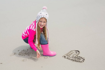 女孩温暖的服装画心形状沙子海滩