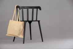 米色彩色的购物袋挂黑色的椅子