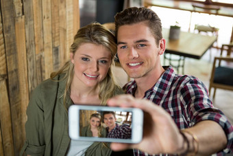 微笑夫妇采取自拍移动电话自助餐厅