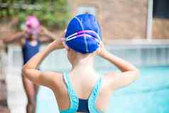 女孩调整游泳护目镜在游泳池边