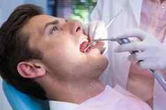 牙医持有医疗设备给治疗病人诊所