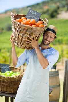 肖像快乐农民携带新鲜的橙子容器