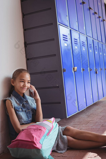 微笑小学女学生会说话的移动电话坐着储物柜